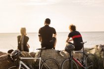 Велосипедисти сидять на береговій лінії на заході сонця — стокове фото