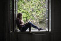 Studentessa seduta sul davanzale della finestra con tablet digitale — Foto stock
