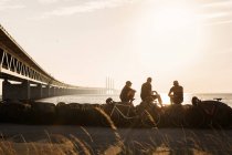 Велогонщики сидят на берегу на закате — стоковое фото