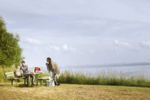 Familia sentada en la mesa de picnic - foto de stock