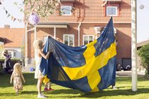 Отец с дочерьми, держащими шведский флаг — стоковое фото