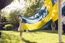 Mädchen hält Schwedenfahne mit Familie im Garten — Stockfoto