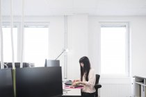 Азиатка, работающая с компьютером — стоковое фото