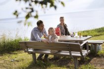 Famiglia seduta al tavolo da picnic — Foto stock