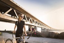 Ciclistas bajo puente en la costa - foto de stock