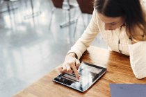 Женщина за столом с помощью цифрового планшета — стоковое фото