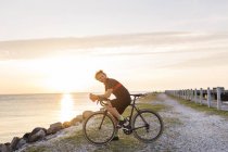 Ciclista em pé na costa rochosa — Fotografia de Stock