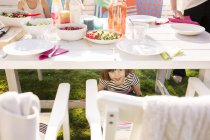 Девушка прячется под столом на вечеринке в саду — стоковое фото