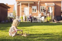 Kleines Mädchen spielt mit Holzspielzeug im Gras — Stockfoto