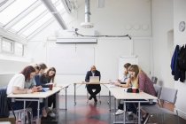 Schüler sitzen bei Vorlesung mit Lehrer im Klassenzimmer — Stockfoto