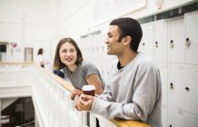 Two students standing by railing in front of lockers with coffee — Stock Photo