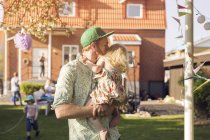 Чоловік носить і цілує доньку на задньому дворі — стокове фото