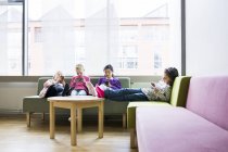 Meninas sentadas no sofá com smartphones — Fotografia de Stock