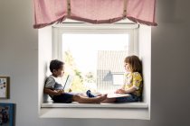 Crianças sentadas no peitoril da janela — Fotografia de Stock