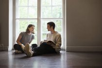Dos estudiantes sentados en el piso y hablando en la universidad - foto de stock