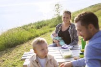 Family sitting at picnic table — Stock Photo