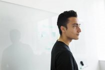 Side view of man standing next to whiteboard in office — Stock Photo