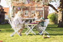 Дети сидят за столиком для пикника в саду — стоковое фото