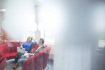 Коллеги сидят на красном диване и разговаривают — стоковое фото