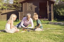 Padre giocare gigante pick up bastoni con figlia e figlio in giardino — Foto stock