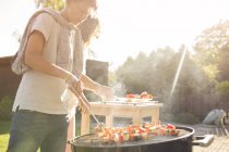 Mature woman and teenager barbecuing at garden party — Stock Photo