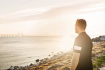 Uomo in abbigliamento sportivo guardando il mare — Foto stock