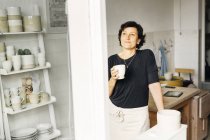 Жіночий гончар тримає чашку кави — стокове фото