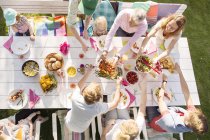 Вид сверху на семью, сидящую за обеденным столом на садовом празднике в заднем дворе — стоковое фото