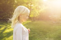Side view of blonde girl in garden — Stock Photo