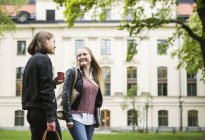 Dos estudiantes hablando en el patio de la universidad con una taza de café - foto de stock