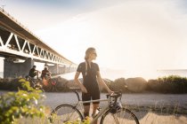 Cyclists under bridge at coastline — Stock Photo