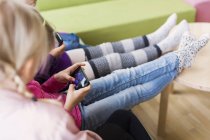 Drei Mädchen sitzen mit Smartphones — Stockfoto