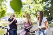 Teenage girls with bicycles (14-15) walking in park — Stock Photo