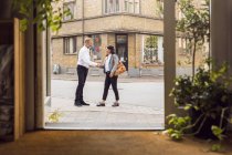 Senior man and woman shaking hands on city street — Stock Photo