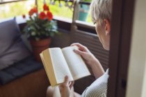 Mujer leyendo libro en balcón - foto de stock