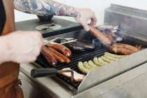 Mid section of man preparing sausages on grill — Stock Photo