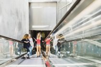 Drei junge Frauen auf Rolltreppe — Stockfoto