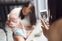 Mulher fotografando mãe com filho bebê (2-5 meses) no café — Fotografia de Stock