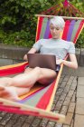 Frau benutzt Laptop tagsüber auf Hängematte — Stockfoto