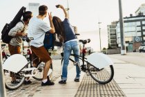 Trois personnes avec des vélos se photographiant en ville — Photo de stock