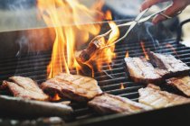 Nahaufnahme eines Mannes, der Fleisch auf dem Grill zubereitet — Stockfoto
