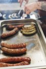 Gros plan de l'homme préparant des saucisses sur le gril — Photo de stock