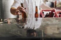 Mid section of brewery worker holding beer bottles — Stock Photo