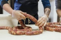 Средняя секция мужчин, делающих свиные колбаски — стоковое фото