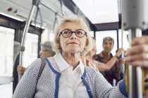 Donna anziana che tiene corrimano in autobus — Foto stock