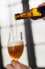 Nahaufnahme eines Brauereimitarbeiters, der Bier aus der Flasche ins Glas gießt — Stockfoto
