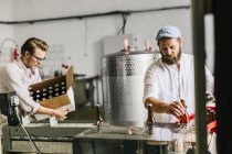 Brewery workers putting beer bottles into boxes — Stock Photo