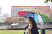 Woman standing under colorful umbrella, concert in background — Stock Photo
