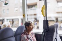 Жінка сидить у автобусі і дивиться через вікно — стокове фото