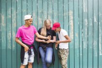 Teenage girl and teenage boys (14-15) looking at smarphone — стоковое фото